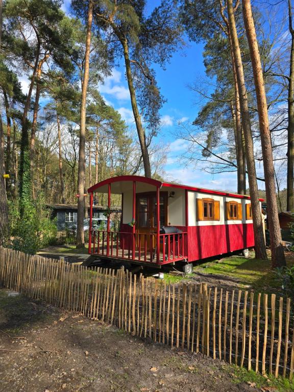 un vagón de tren rojo sentado junto a una valla de madera en pipowagen met prive Hot tub, en Lanaken