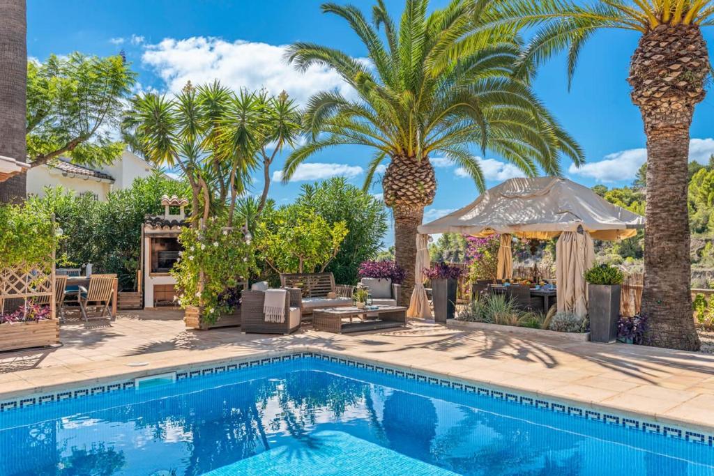 a pool with palm trees and a gazebo at Villa Domingo - PlusHolidays in Benissa