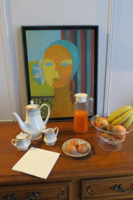 une table avec un bol de fruits et une peinture d'une femme dans l'établissement Molibeau, à Beauvais