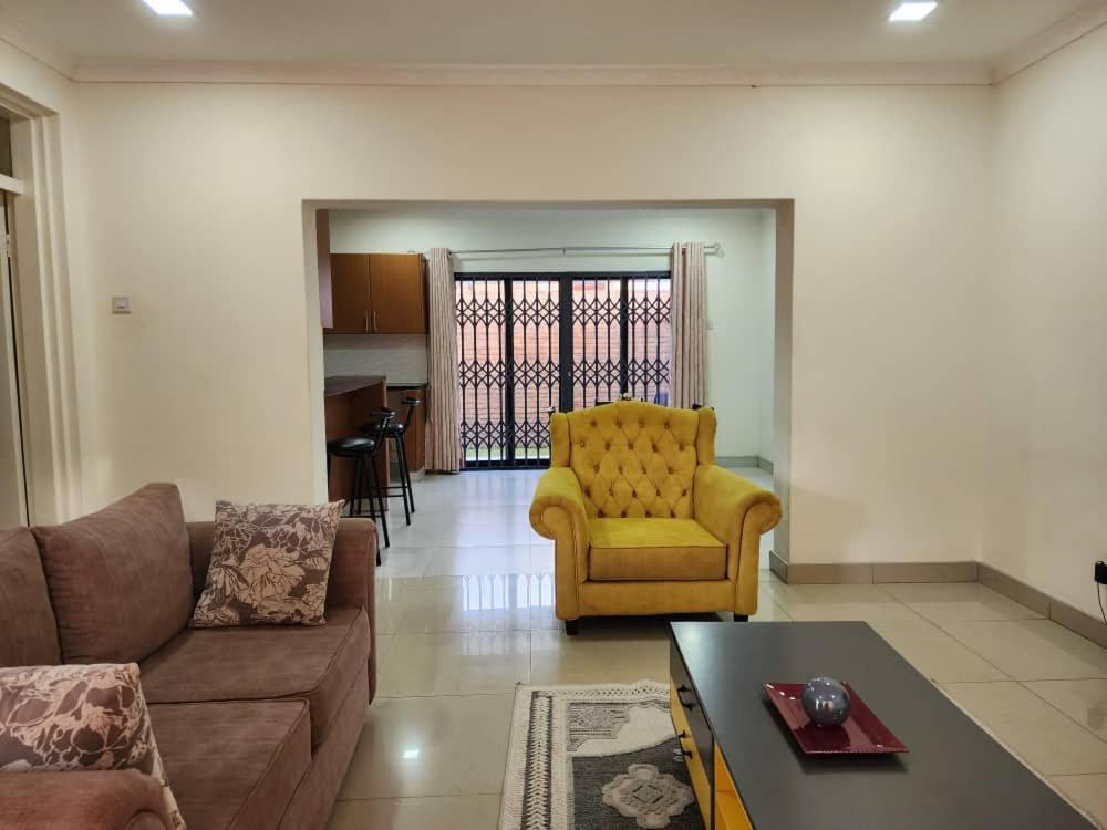 sala de estar con sofá y silla amarilla en Modern & secure apartment in Area 43 Lilongwe - self catering, en Lilongwe