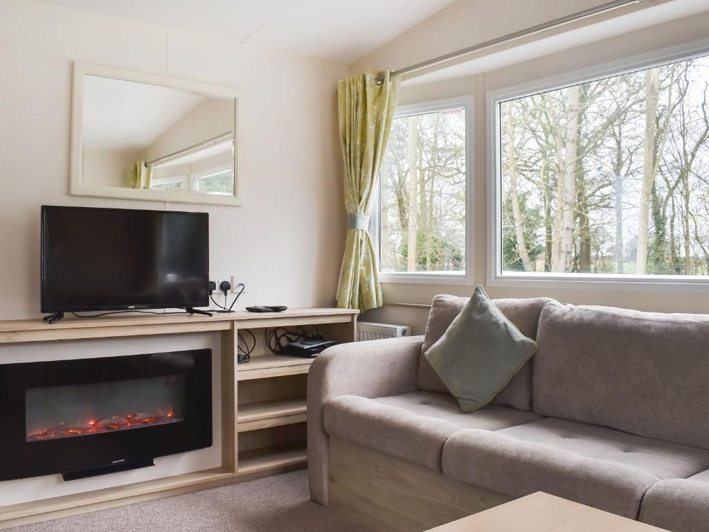 a living room with a couch and a television at Meres Retreat in Saxmundham