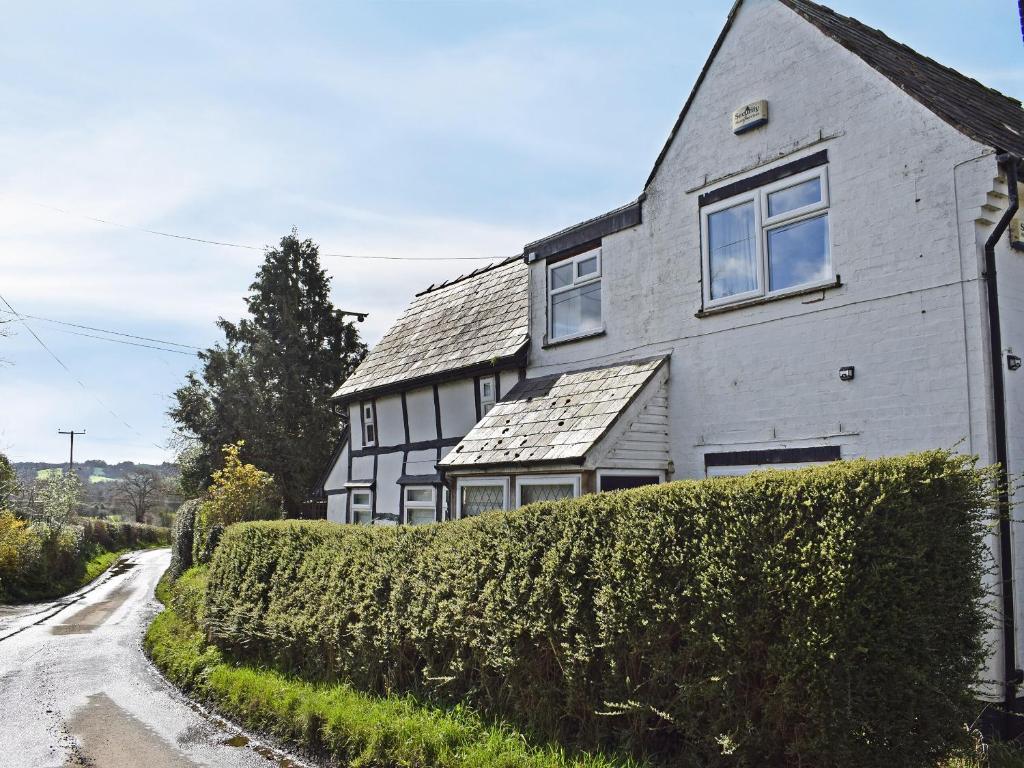 een huis met een heg voor een weg bij Merrow Cottage in Ledbury