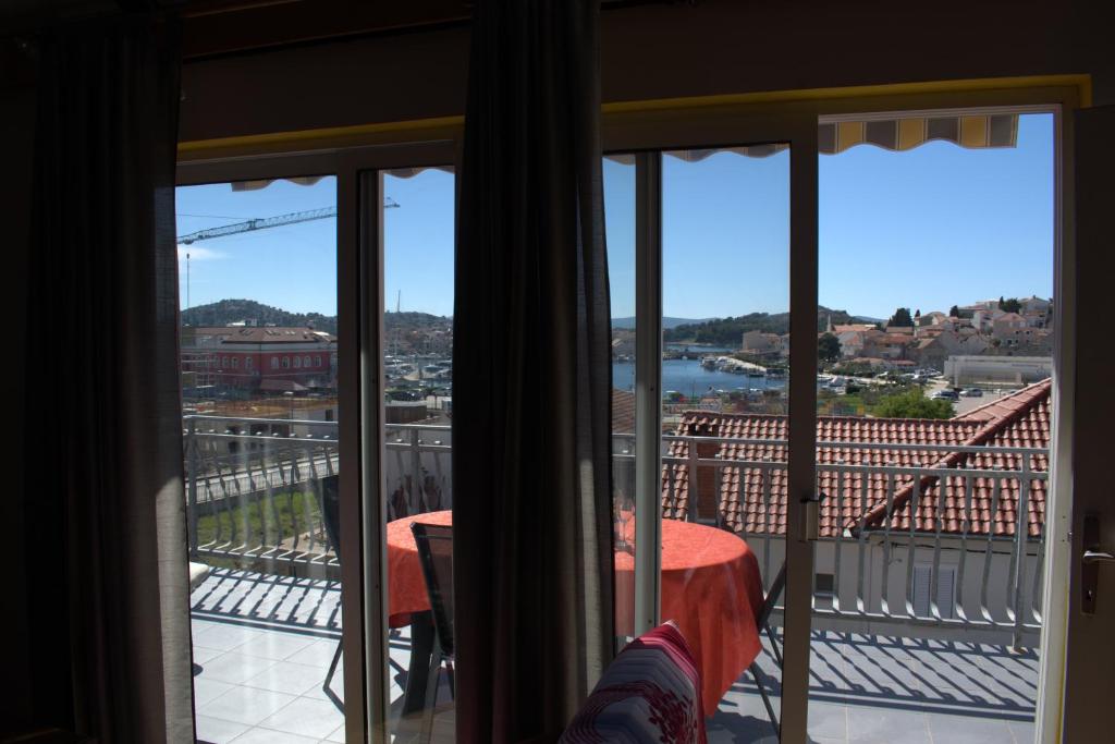 a woman sitting on a balcony looking out the window at Apartman Marko in Tribunj