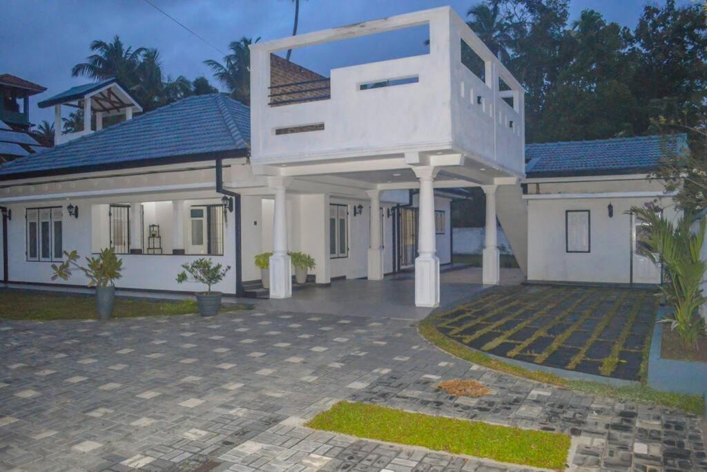 una grande casa bianca con un balcone sopra di Villa Silversands, Negombo a Negombo