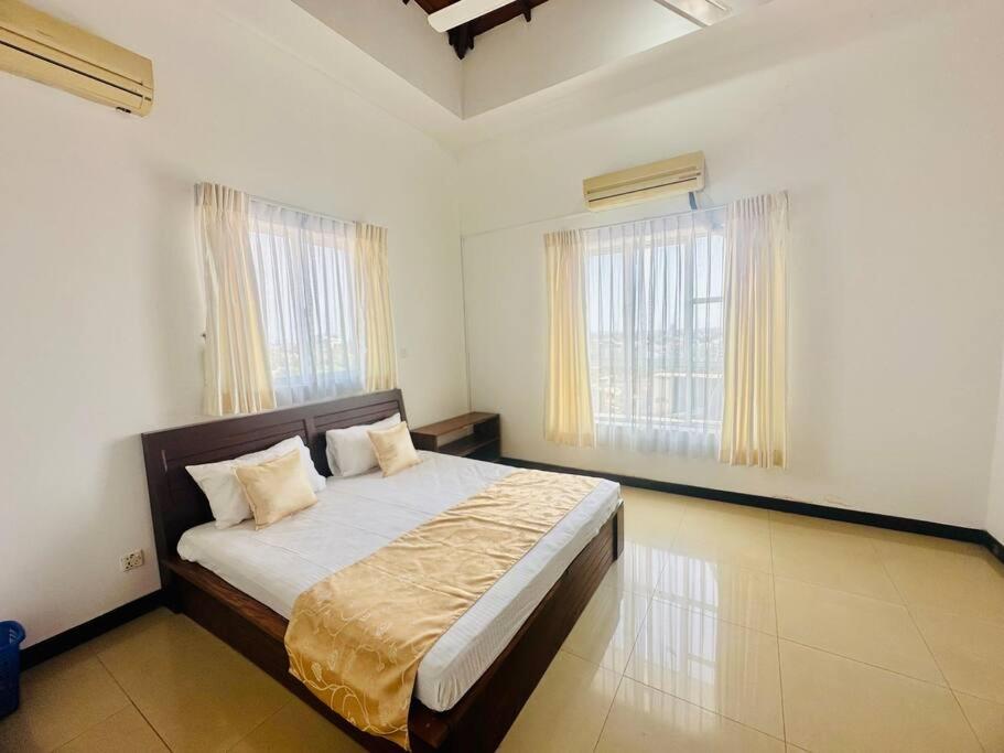 a bedroom with a bed and two windows at Wimbledon Two Rooms Apartment in Colombo