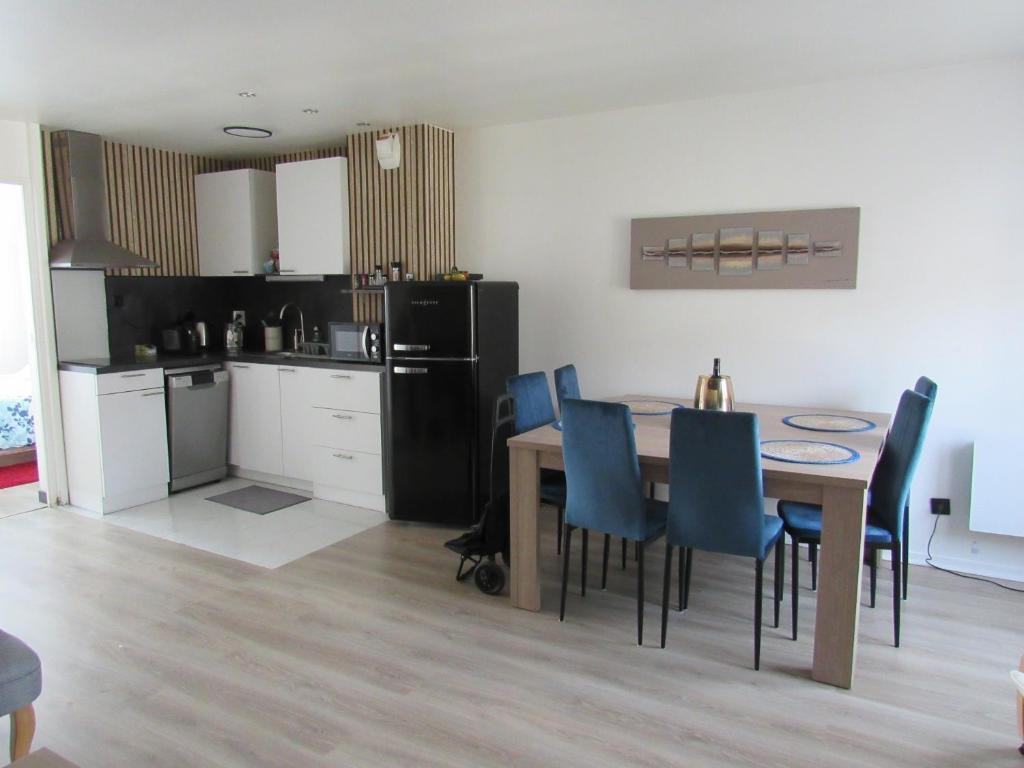 a kitchen and dining room with a table and blue chairs at Appartement 3 pièces proche Disneyland in Magny-le-Hongre