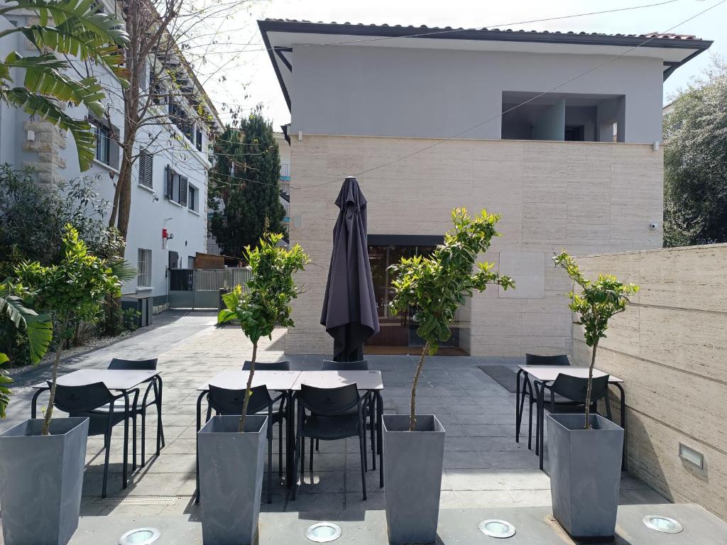 a patio with tables and chairs and an umbrella at Hotel Sitges Rooms in Sitges