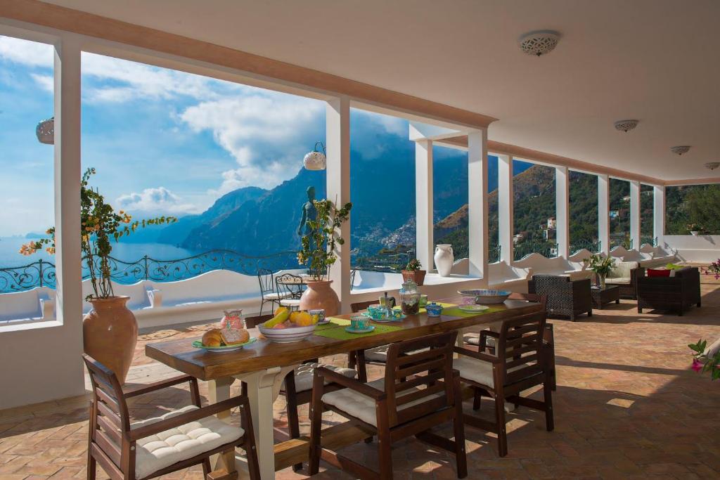 - une salle à manger avec une table et une vue sur la montagne dans l'établissement Villa Santa Chiara Positano Suites, à Positano