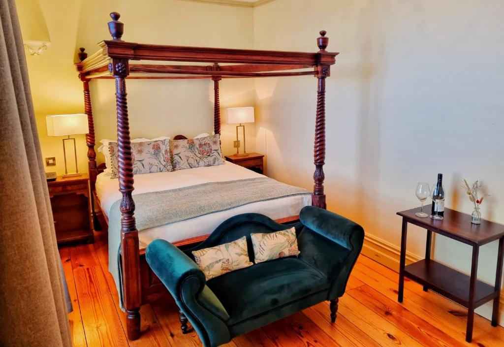 um quarto com uma cama de dossel e uma cadeira verde em Newbay House Wexford em Wexford