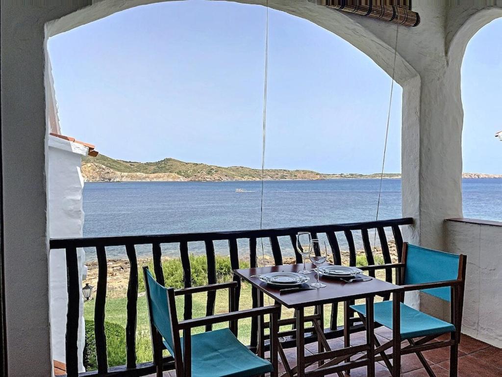 einen Tisch und Stühle auf einem Balkon mit Meerblick in der Unterkunft P107 Un rinconcito en el mar in Fornells