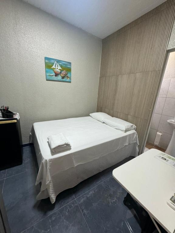 um pequeno quarto com uma cama e uma mesa em Pousada da Celma em Fortaleza