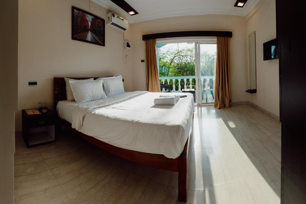 a bedroom with a large bed and a large window at Tony's beach house in Calangute