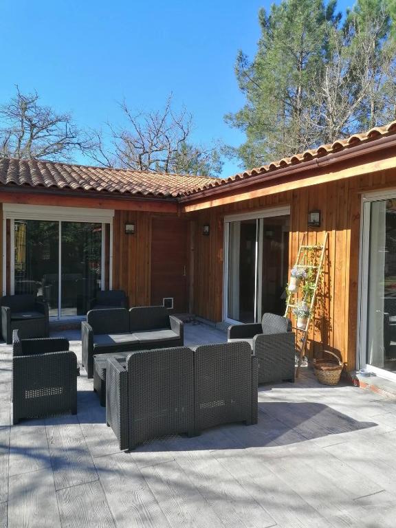 une terrasse avec des canapés, une table et des chaises dans l'établissement Villa de vacances, à Grayan-et-lʼHôpital