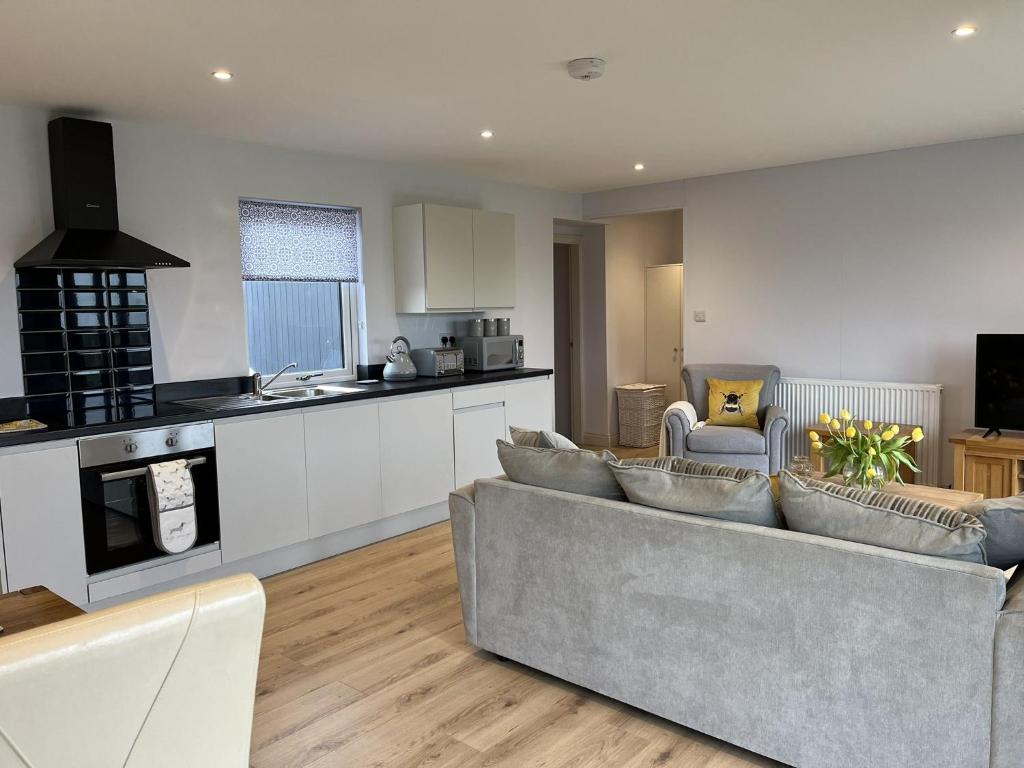 a living room with a couch and a kitchen at Fleetwood 2 bed cottage in Tunstall