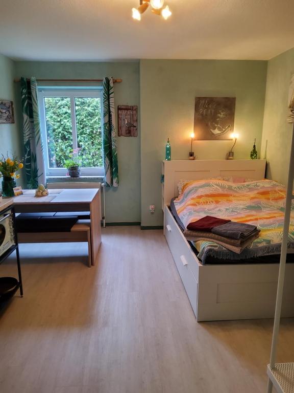 a bedroom with a bed and a desk and a window at Studio-Apartment mit kleinem Gartenanteil in Burg auf Fehmarn