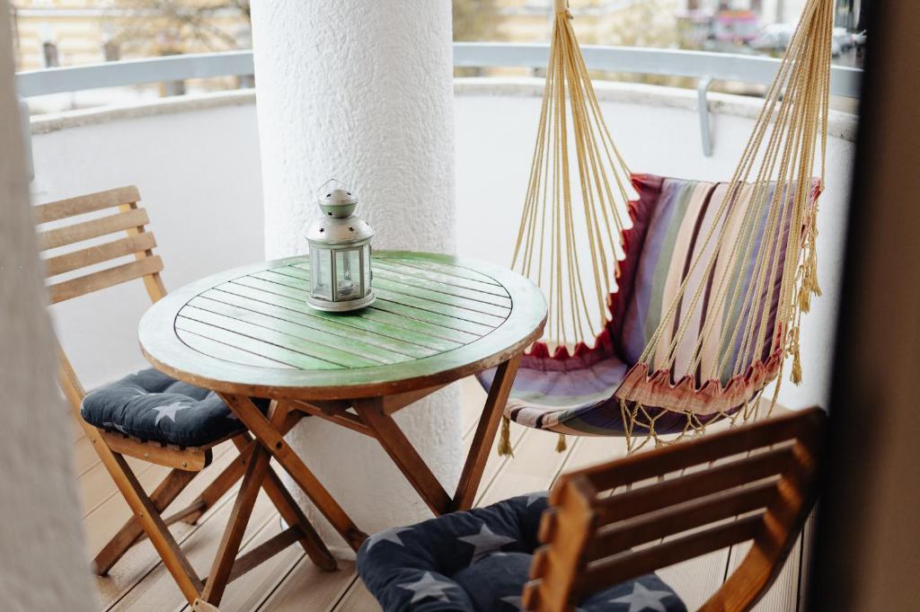 a table and two chairs on a porch with a hammock at Cool Opera Apartments in Cluj-Napoca