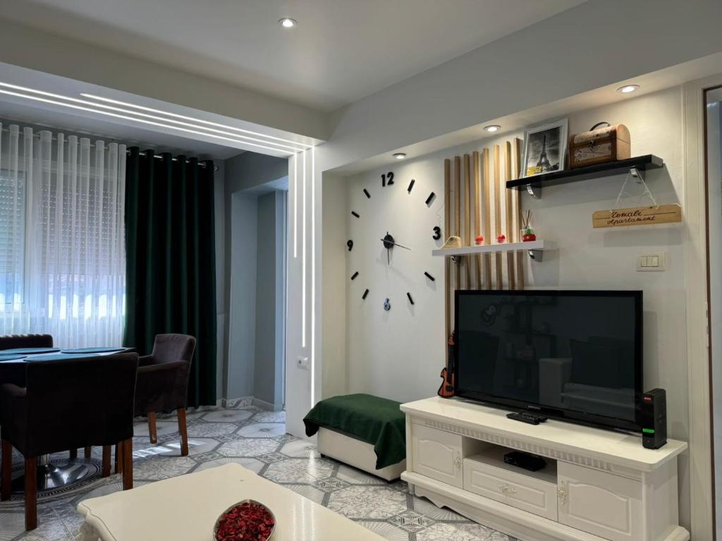 ein Wohnzimmer mit einem TV und einer Uhr an der Wand in der Unterkunft Temali Apartment in Shkodra