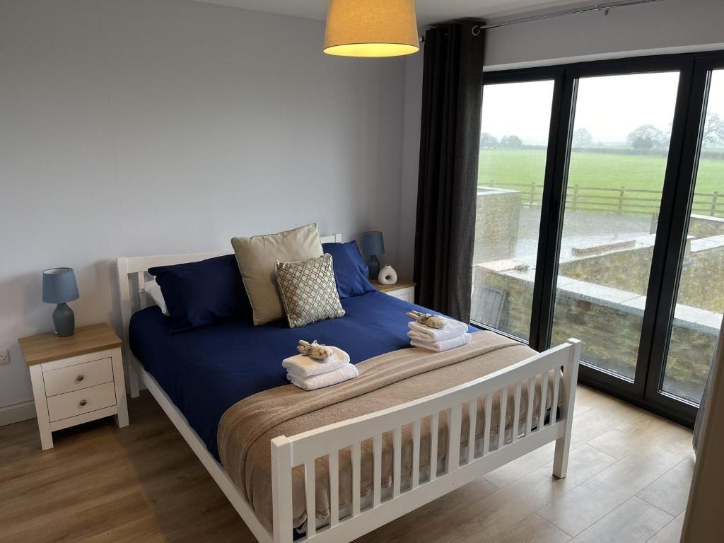 1 dormitorio con cama con sábanas azules y ventana en Genesis 1 bed cottage, en Tunstall
