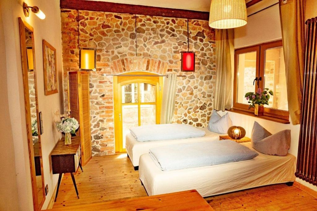 two beds in a room with a stone wall at Studio Brennerei Haselberg in Wriezen