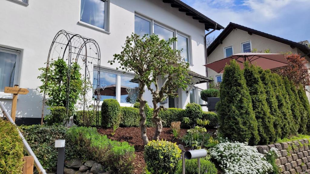 un jardín frente a una casa con árboles y arbustos en Ferienwohnung Friedhoff, 80qm, en Schmallenberg