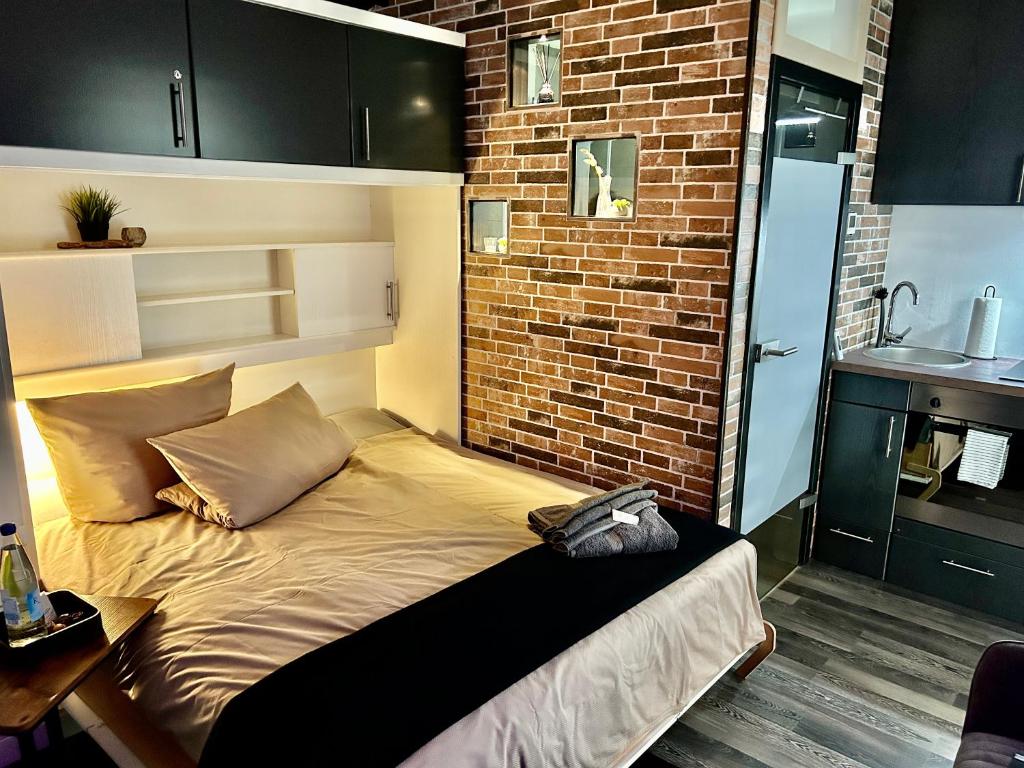 Ce lit se trouve dans une chambre dotée d'un mur en briques. dans l'établissement LIVE-IN Tiny Studiowohnung, à Wertheim