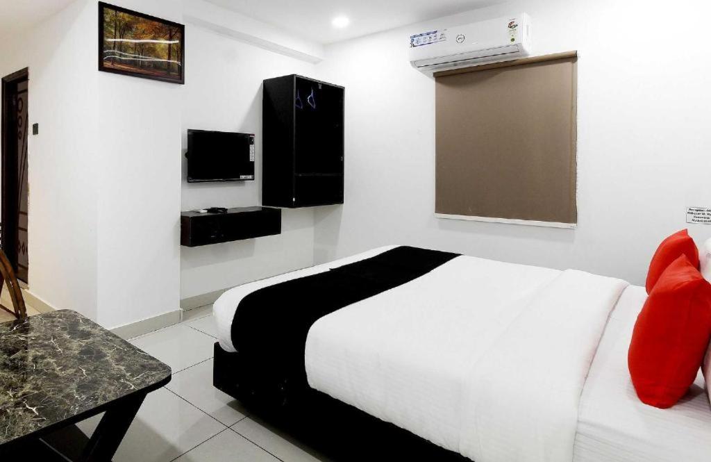 a white bedroom with a bed and a tv at Hotel Mythri in Secunderabad