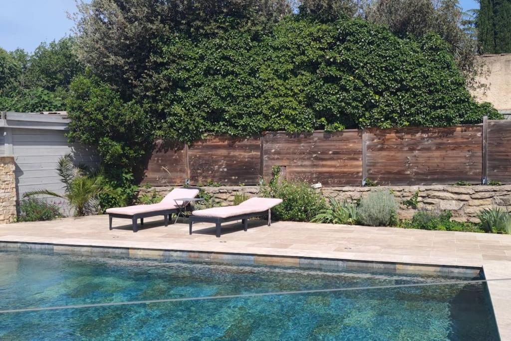 2 bancs installés à côté d'une piscine dans l'établissement Maison tout confort en garrigue, à Boisseron