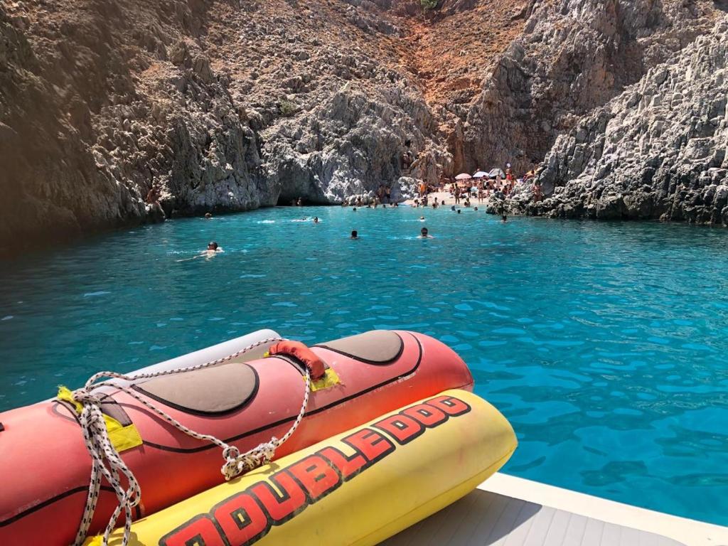 una balsa en el agua con gente nadando en una cueva en Boat trip and diving experiences in Apokoronas en Vamos