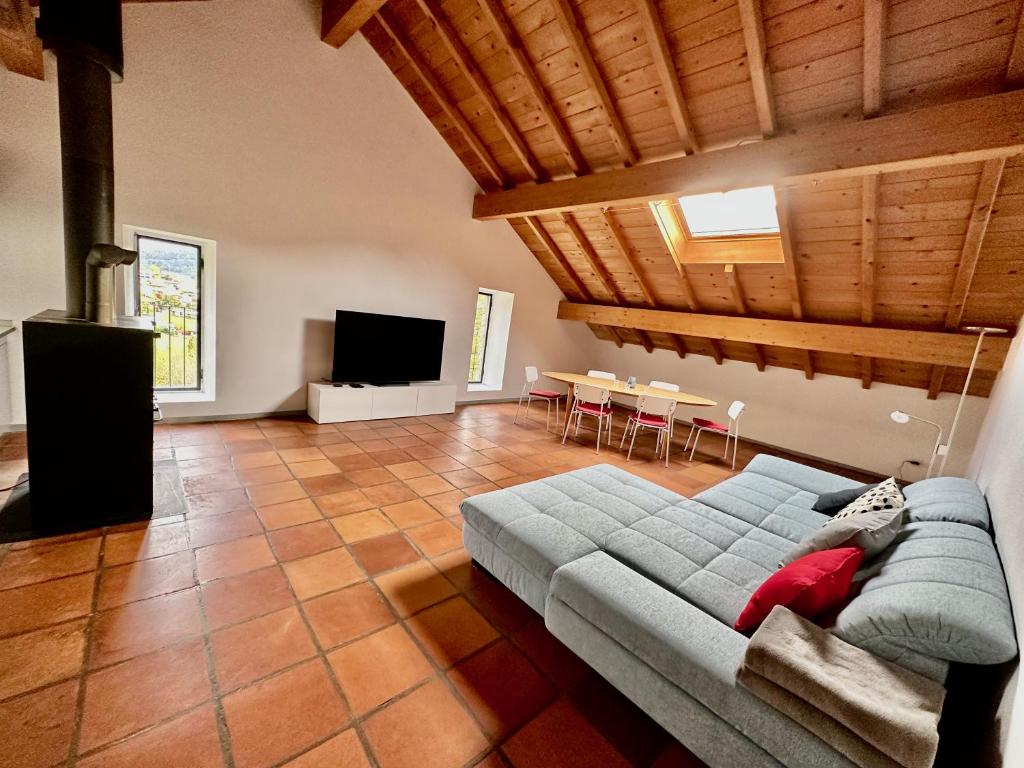 ein Wohnzimmer mit einem Sofa und einem TV in der Unterkunft Grosszügige Dachwohnung in Tessiner Altbau in Monte Ceneri
