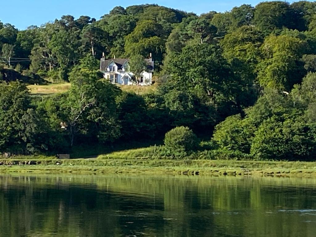 a house on a hill next to a body of water at Glenaros Lodge in Salen