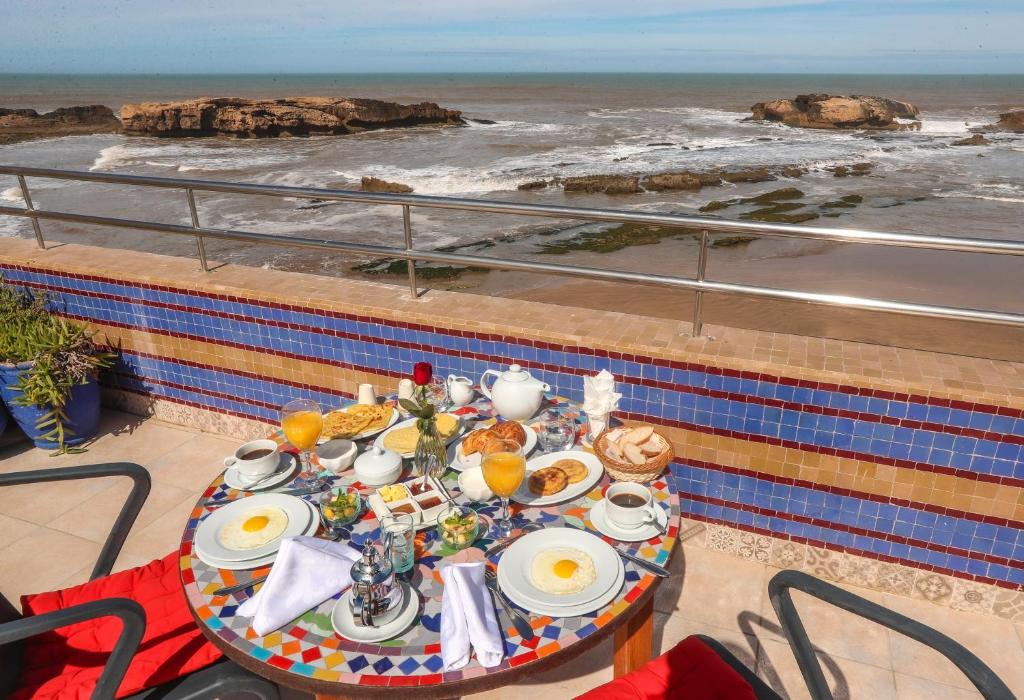 uma mesa com pequeno almoço na varanda com vista para o oceano em Riad Perle D'Eau em Essaouira