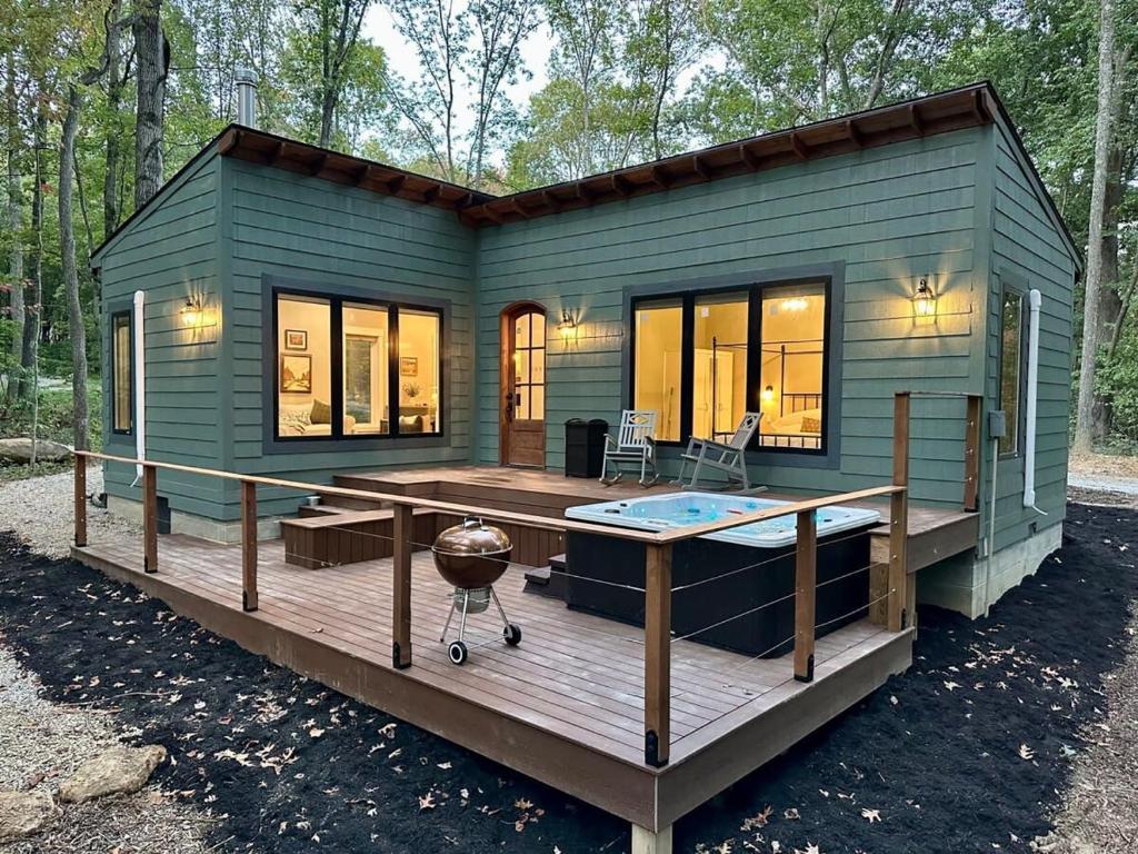 a green tiny house with a deck and a hot tub at Brand New Modern Cottage Hocking Hills in Stella