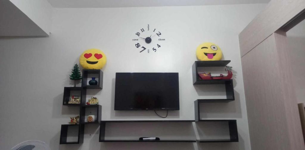 a living room with a tv and two faces on the wall at 1 Bedroom Cozy Condo Unit with Netflix & Free Wifi in Trees Residences in Manila