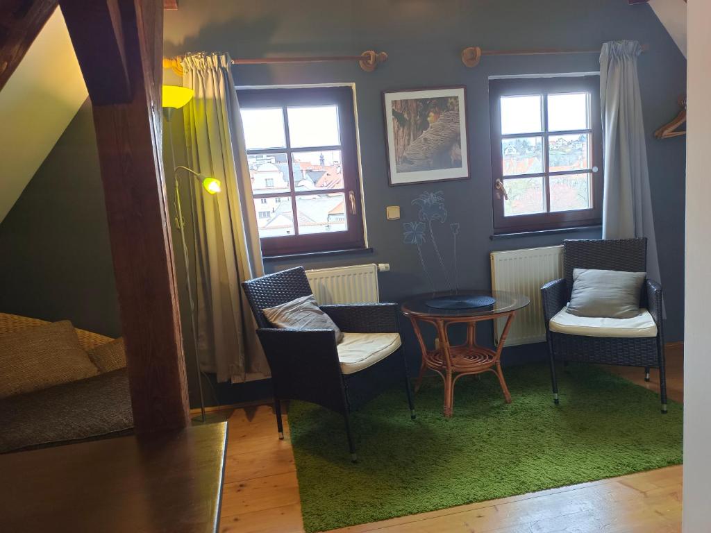 a living room with chairs and a table and windows at Guest House Olšakovský in Český Krumlov