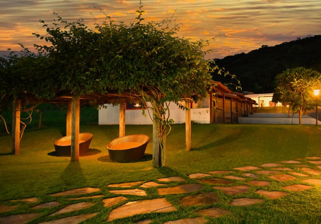 un jardín con árboles y un camino de piedra al atardecer en Pousada Vila do Lago en Capitólio