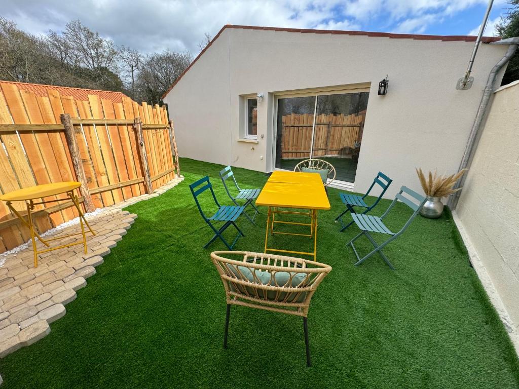 d'une terrasse avec une table jaune et des chaises sur gazon. dans l'établissement Sérénité aux Nids du Petit Bois pour un séjour détente en Charente Maritime, à Breuillet