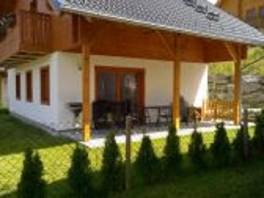 una casa con porche y un patio con árboles en Schönes Ferienhaus in Sankt Margarethen Im Lungau mit Terrasse, Grill und Garten en Sankt Margarethen im Lungau