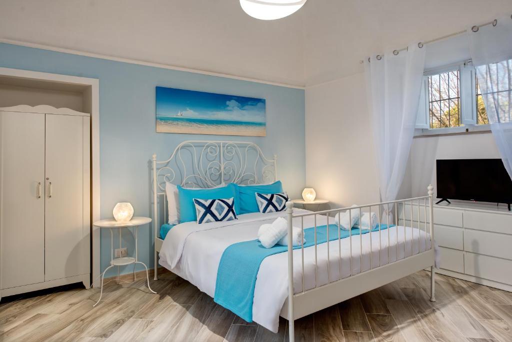 ein blau-weißes Schlafzimmer mit einem Bett und einem TV in der Unterkunft Il giardino di aranci e limoni in Piano di Sorrento