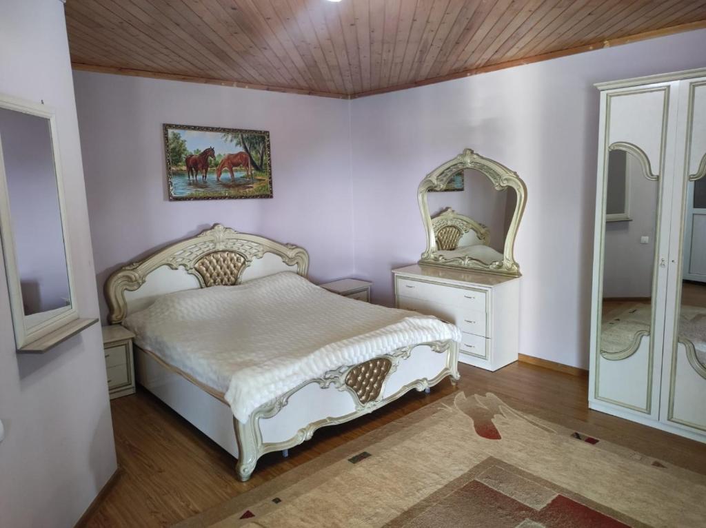a bedroom with a white bed and a mirror at Жемчужина Иссык - Куля in Cholpon-Ata