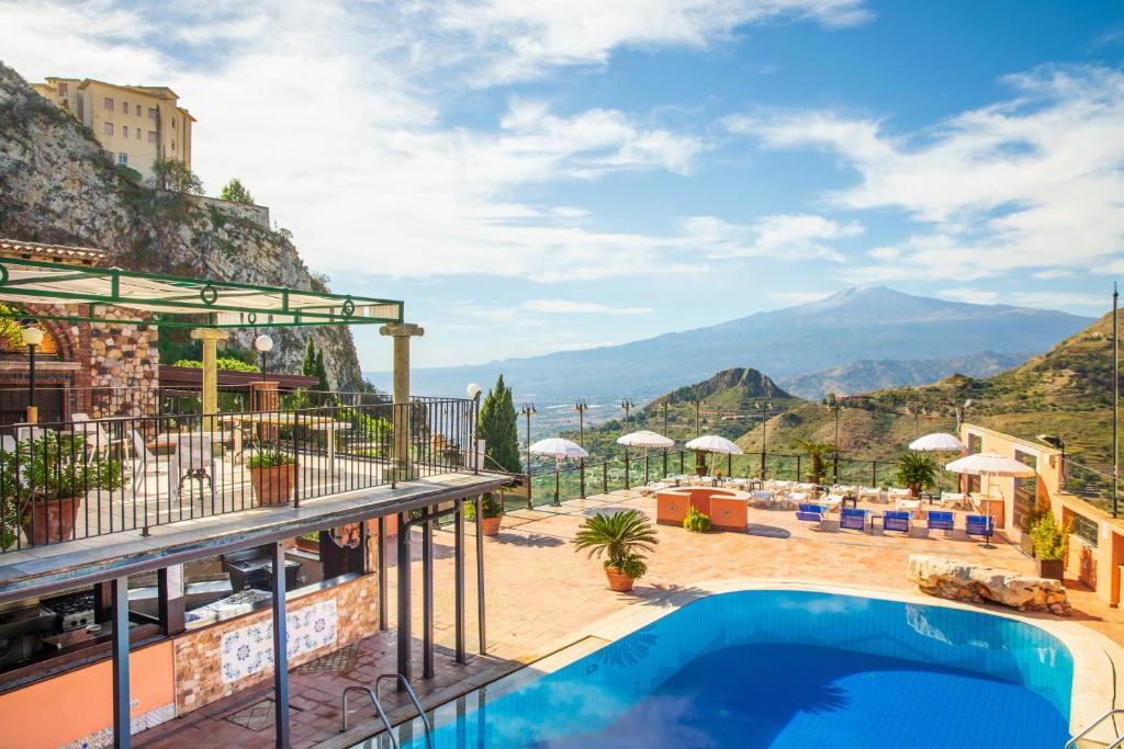 a hotel with a pool and mountains in the background at Hotel Villa Sonia in Taormina
