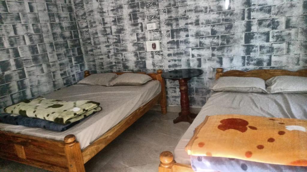 a bedroom with two beds and a brick wall at Vasu estate stay in Madikeri