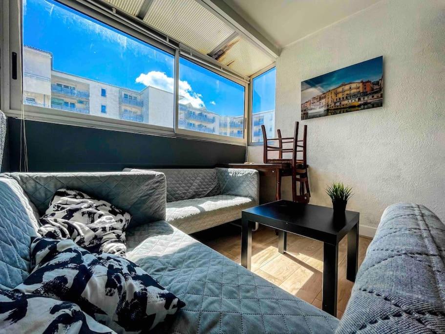 un salon avec un canapé et une grande fenêtre dans l'établissement Petite perle, à 2 pas de la gare et du centre, à Sète