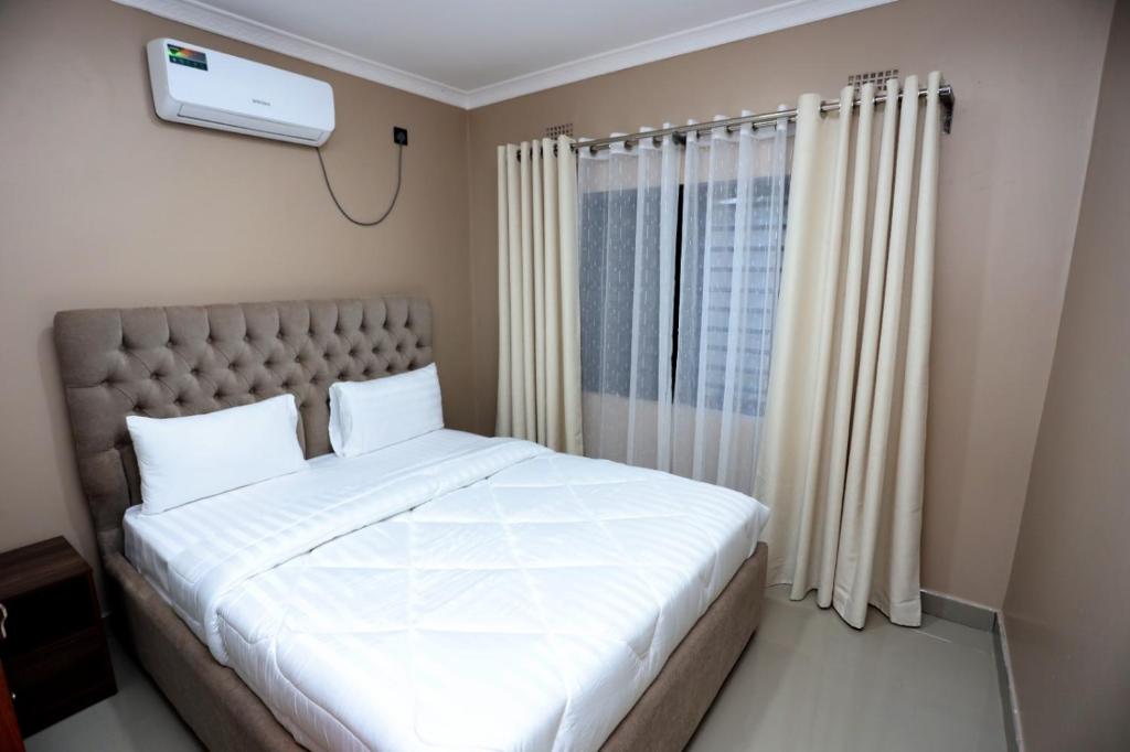 a bedroom with a large white bed and a window at Cloud One Apartments in Kitwe