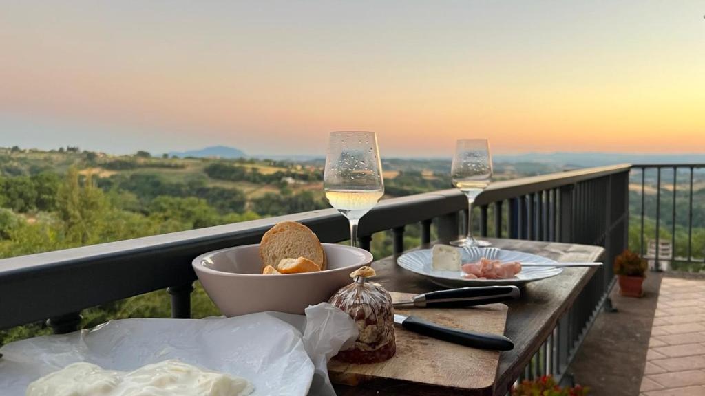 una mesa con un tazón de comida y dos copas de vino en POGGIO&TRAMONTO, en Otricoli