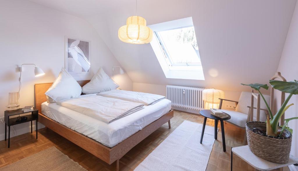 Un dormitorio con una cama con sábanas blancas y una ventana. en WÄLDER: Quartier Birkle in Titisee, en Titisee-Neustadt