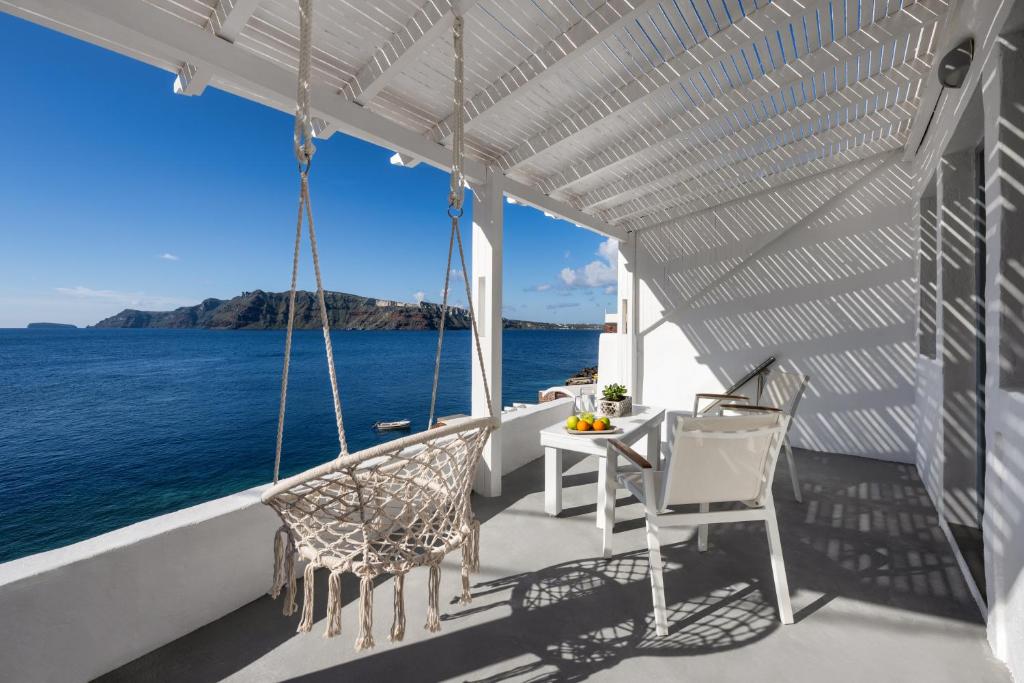 un porche con sillas y una mesa sobre el agua en Lava Stone en Oia