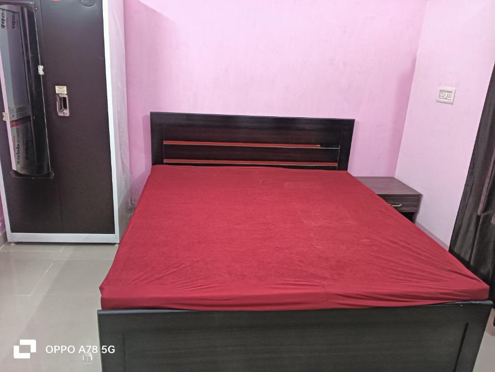 een slaapkamer met een bed met een rode deken erop bij KRISHNA VILLA HOMESTAY, AYODHYA in Ayodhya
