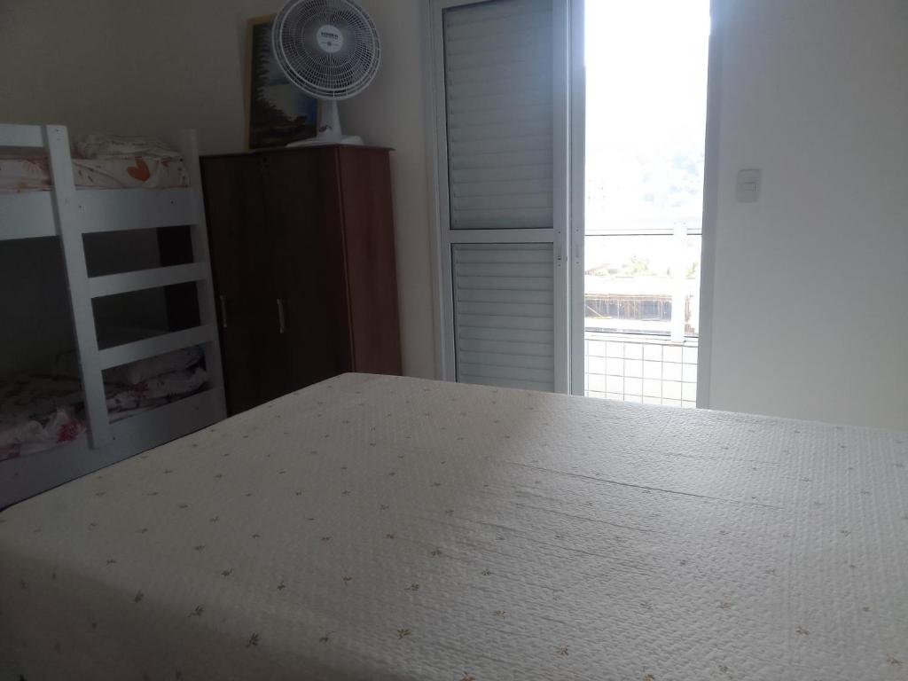 een slaapkamer met een wit bed en een raam bij Praia in Praia Grande