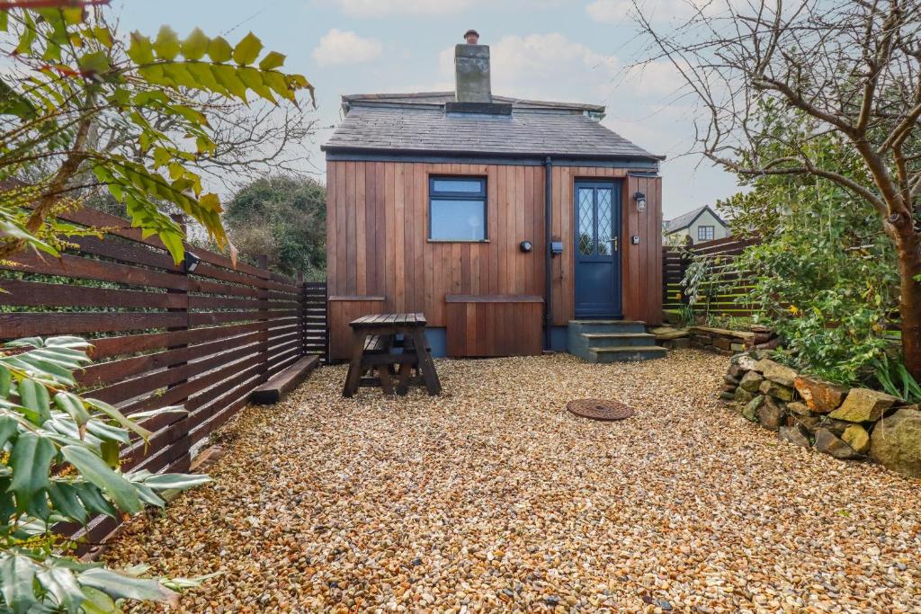 a tiny house with a blue door and a bench at Perranglaze in Truro