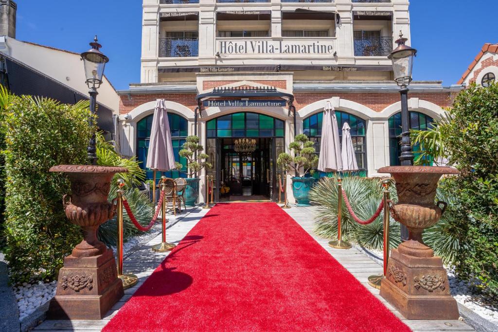 un chemin de tapis rouge devant un bâtiment dans l'établissement Hôtel Villa-Lamartine, à Arcachon